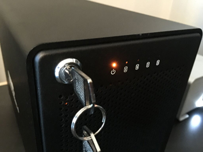 Close-up of a black device with a key in a lock and a glowing orange power indicator light.