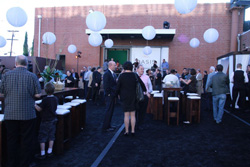 People socializing at an outdoor evening event decorated with large hanging white spherical lanterns.