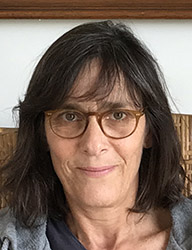 A woman with shoulder-length dark hair and brown-rimmed glasses smiling slightly.