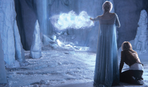 A woman in a long blue dress reaches toward a glowing blue mist inside a cavern of ice.