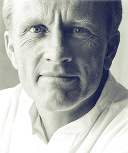 A close-up, black and white portrait of a middle-aged man looking directly at the camera.