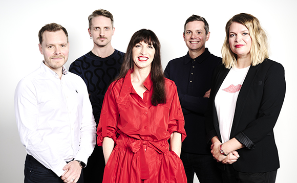 Five people, including a woman in a red dress, posing together against a white background.