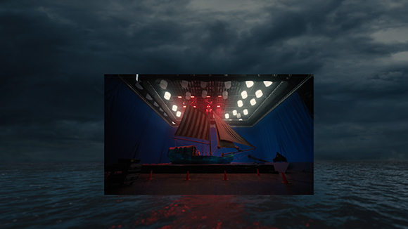 A small blue boat sits under bright overhead lights in a dark room with blue curtains.