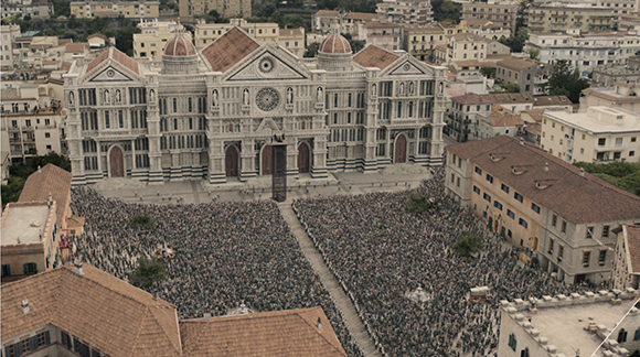 Aerial view of a massive crowd filling a large plaza in front of a large, ornate cathedral.