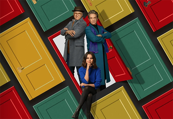 Three people pose amidst a pattern of tilted red, yellow, and green doors.