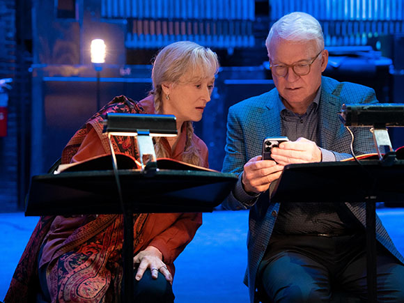 A woman and a man lean in to look at a smartphone held by the man.