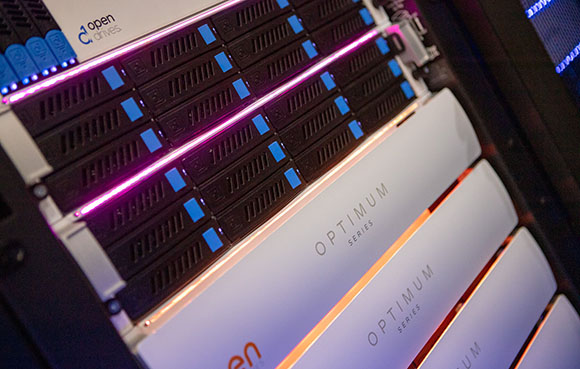 Close-up of a server rack with black drive bays and glowing pink and orange lights.