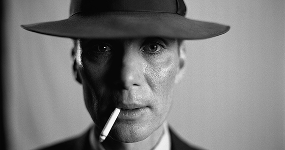 Black and white close-up of a man wearing a wide-brimmed hat with a cigarette in his mouth.
