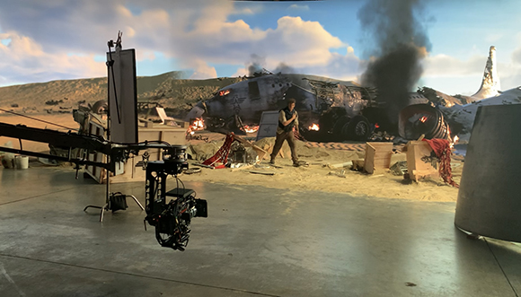 A film studio set with a large crashed airplane prop, smoke, and camera equipment.