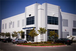 A white two-story modern office building with large glass windows under a clear blue sky.