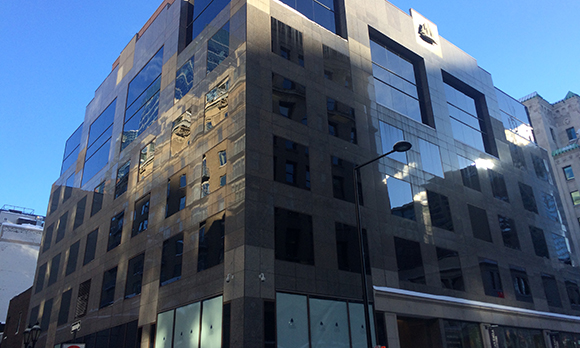 A large dark building with reflective glass windows under a clear blue sky.
