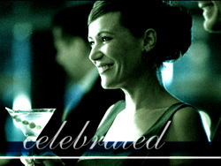 A smiling woman in formal attire holds a martini glass at a social gathering.