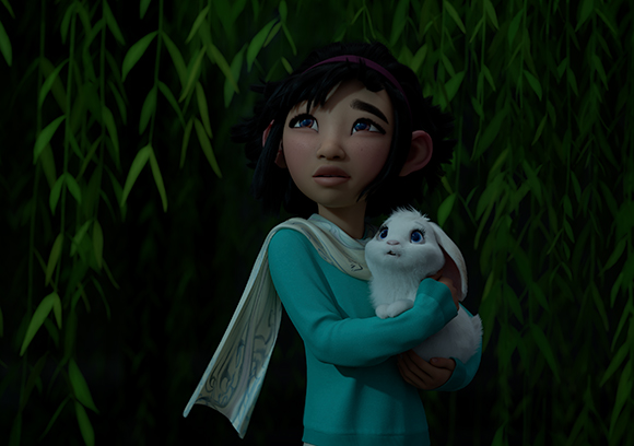 A young girl with dark hair and a teal shirt holds a small white rabbit against green willow leaves.