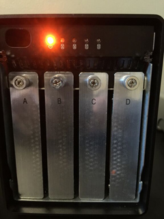 A black electronic device with four vertical metal plates labeled A, B, C, and D, and a glowing orange light.