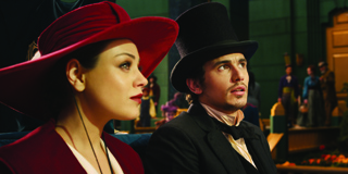 A woman in a wide-brimmed red hat and a man in a black top hat look toward the side.