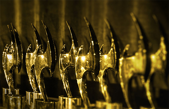 A row of shiny, golden crescent-shaped awards lined up on a dark surface.