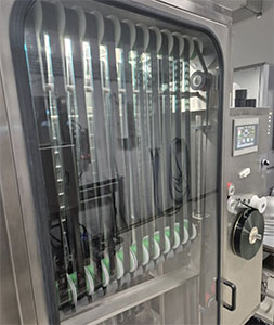 Vertical metal rods visible through the glass door of a stainless steel industrial machine.