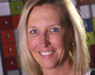 A smiling blonde woman with blue eyes looking directly at the camera.