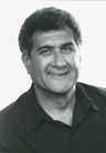 Black and white headshot of a middle-aged man with dark, wavy hair smiling at the camera.