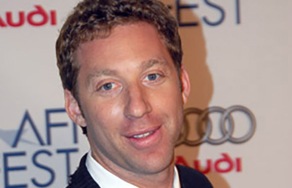 A man with curly brown hair smiling at an event with Audi and AFI Fest logos in the background.
