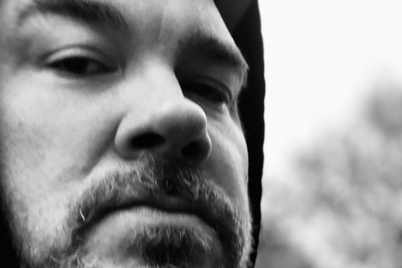 Black and white close-up of a man with a mustache and beard looking toward the camera.