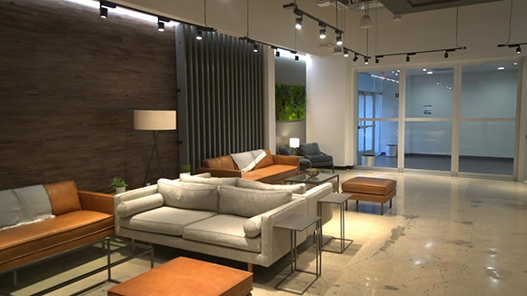 A modern lounge with leather and fabric sofas, coffee tables, and track lighting in a spacious room.