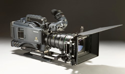 A professional cinema camera equipped with a large lens, matte box, and top handle on a neutral background.
