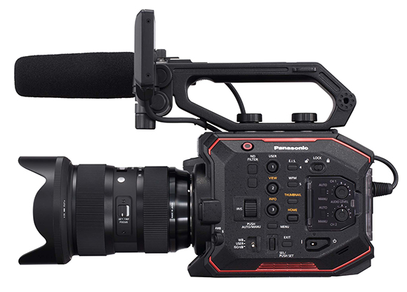 A black Panasonic professional video camera with a large lens and a microphone with a foam windscreen.