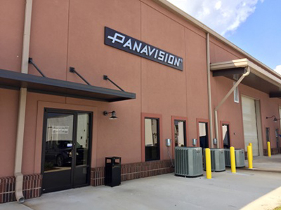 A tan commercial building with a large black Panavision sign mounted on the wall above an entrance.