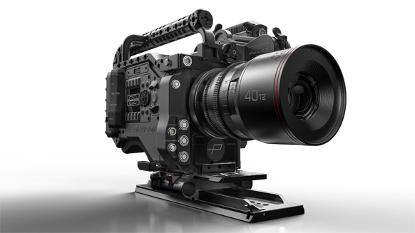 A black professional cinema camera with a large prime lens mounted on a base plate against a white background.