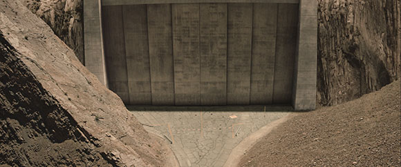 A massive concrete dam wall situated between two steep, rocky canyon walls.