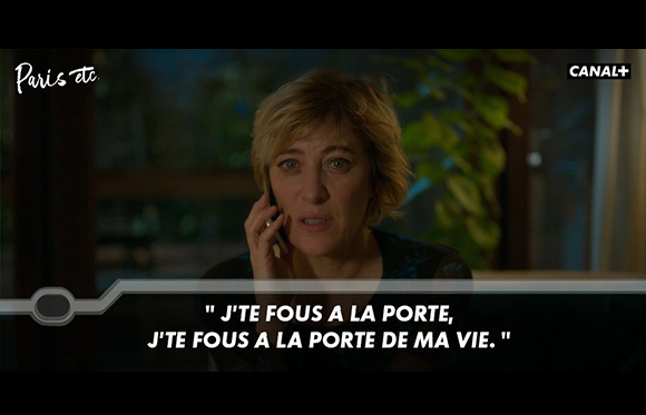 A blonde woman speaks into a cell phone with French text overlaid at the bottom.