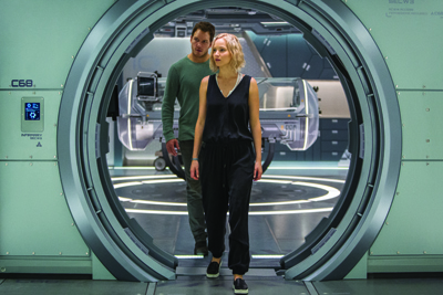 A man in green and a woman in black stand in a circular metallic doorway of a sci-fi spaceship.