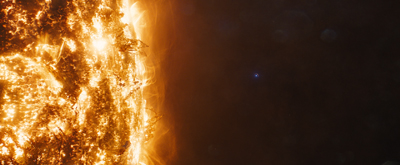 A close-up view of the sun's glowing, textured surface with bright solar flares against a dark background.