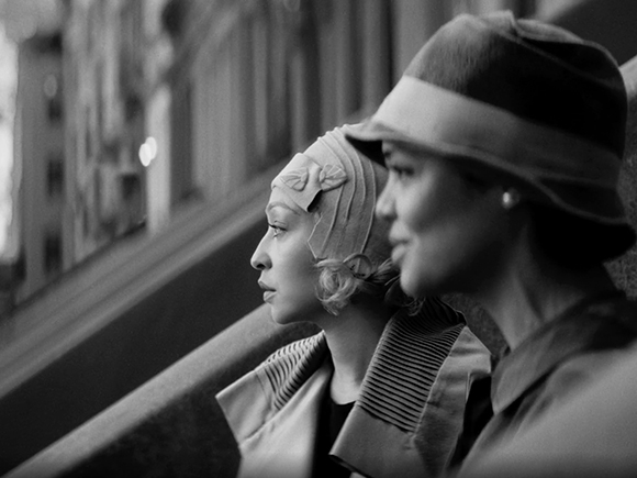 Black and white profile of two women wearing 1920s style cloche hats looking out a window.
