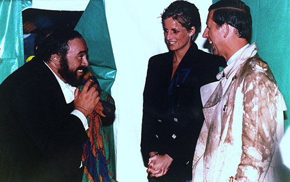 A man with a beard talks to a woman in a black blazer and a man in a light-colored jacket.