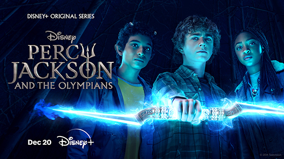 Three teenagers stand together in a dark forest, holding a glowing blue sword toward the camera.