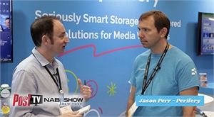 Two men in collared shirts and lanyards talk in front of a blue media storage solutions backdrop.