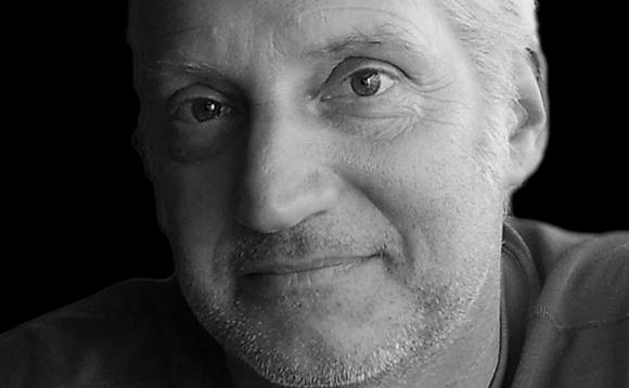 Black and white close-up portrait of a middle-aged man with short hair and light facial hair smiling.
