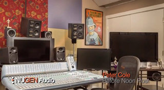 A mixing console with multiple studio monitors, computer screens, and a poster on the wall.