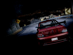 A red car speeds along a dark, winding mountain road at night under dim lights.