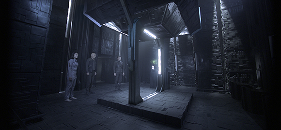 Three people in jumpsuits stand in a dark, metallic, futuristic hallway with glowing lights.