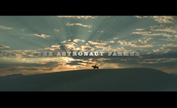 Sunlight rays break through clouds over a silhouette of a person on a horse atop a hill.