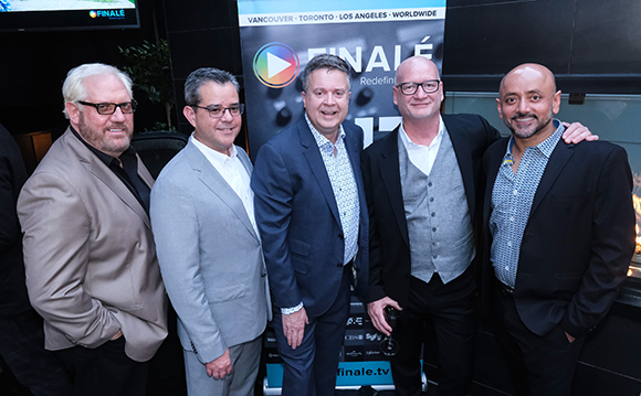 Five men in business casual attire standing in a row and smiling for a group photo.