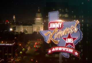 A neon sign shaped like Texas reading 'Jimmy Kimmel Live! Austin' against a night city skyline.