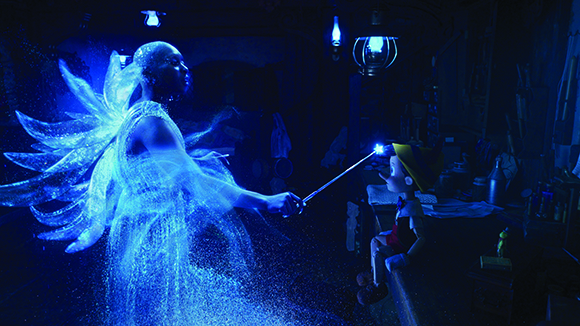 A glowing blue fairy figure points a sparkling wand at a small puppet sitting in a dark room.