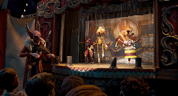Puppet characters perform on a small, ornate stage in front of an audience.