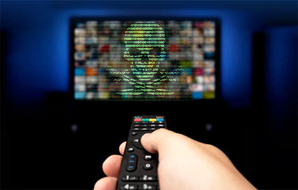 A hand holds a remote control toward a blurred television screen displaying a padlock shape made of binary code.