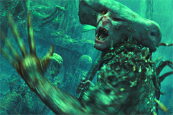 A green-tinted creature with a wide, flat head and an open mouth reaches a clawed hand toward the camera.