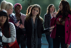 A group of diverse young women standing in a crowd, some looking skeptical or surprised.